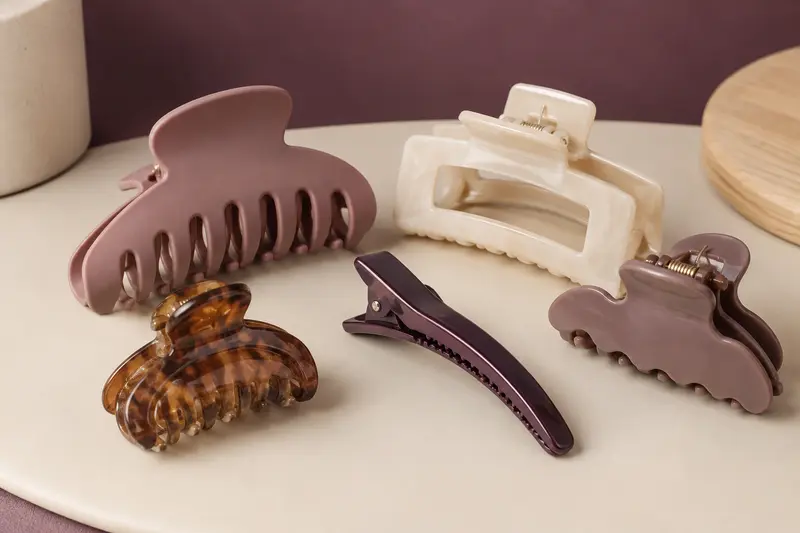 Pinces de séparation de coiffure regroupées sur une surface ivoire
