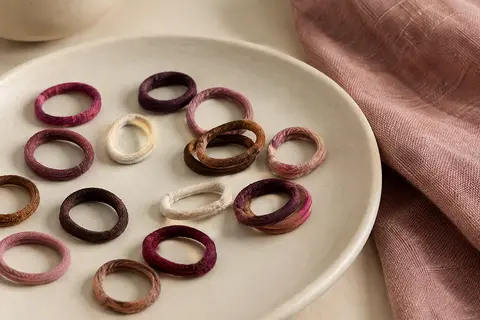 Petits élastiques à cheveux multicolores en caoutchouc et tissu disposés sur une céramique mate