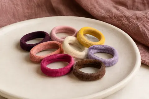 Mini élastiques pour cheveux en polyester multicolore disposés sur un support en céramique mate