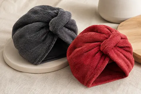 Deux turbans-serviettes en microfibre gris foncé et rouge, pliés pour montrer leur texture et leur nœud