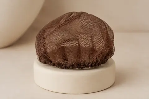 Filet à chignon marron en maille fine posé seul sur un support en céramique crème.